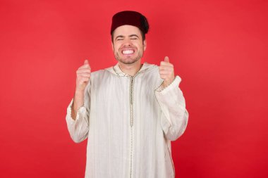 Geleneksel Türk şapkası takan yakışıklı genç adam kollarını kaldırmış ve gözleri kapalı zaferi kutluyor. Kazanan konsept.