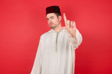 Geleneksel Türk şapkası takan yakışıklı genç adam. Alnında parmakları olan insanlarla dalga geçiyor. Ezik hareketler yapıyor, alay ediyor, hakaret ediyor..