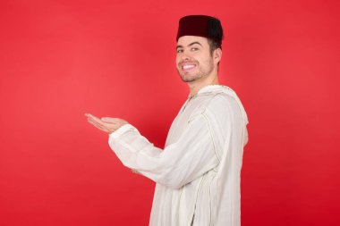 Geleneksel Türk şapkası giyen yakışıklı genç adam Fes fotokopi odasını gösteriyor, reklam sunuyor.  