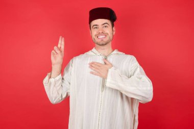 Geleneksel Türk şapkası giyen yakışıklı genç adam el pençe divan yemin ederek sadakat yemini ediyor..