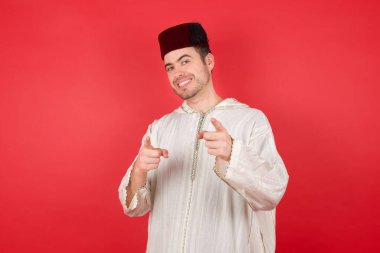 Geleneksel Türk şapkası takan yakışıklı genç adam, mutlu ve komik yüzüyle kamerayı işaret ediyor. İyi enerji ve titreşimler. 