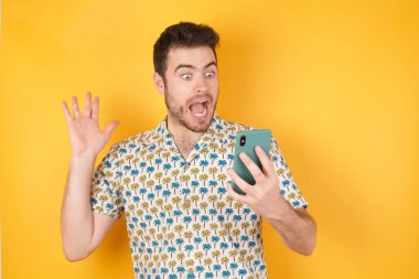 Stüdyo arka planında akıllı telefonla poz veren yakışıklı bir genç.