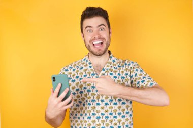 Stüdyonun arka planında akıllı telefonlu çekici bir genç adamın fotoğrafı.