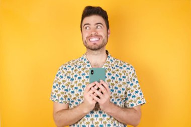 Stüdyonun arka planında akıllı telefonlu çekici bir genç adamın fotoğrafı.