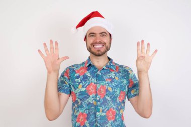 Noel Baba şapkalı genç adam dokuz numarayı gösterip işaret ederken kendinden emin ve mutlu bir şekilde gülümsüyor..