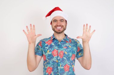 Noel Baba şapkalı genç adam on numarayı gösterip işaret ederken kendinden emin ve mutlu gülümsüyor..