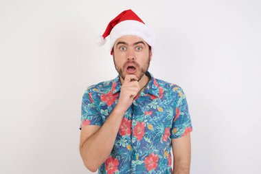 Noel Baba şapkalı genç adam sürpriz bir şekilde ağzını açar ve ani haberlere tepki verir. İnsanlar ve yüz ifadeleri.