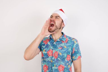 Noel Baba şapkalı genç adam bağırıyor ve ağızdan ağıza bağırıyor. İletişim konsepti.