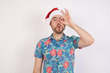 Noel Baba şapkalı genç adam şaşırmış bir yüz ve parmaklarından bakan bir bakışla şoka girdi. İnançsız ifade.