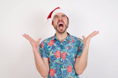 Noel Baba şapkalı genç adam bağırıyor ve bağırıyor agresif bir ifade ve kollar havada. Hayal kırıklığı konsepti.