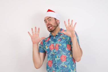 Noel Baba şapkalı genç adam korkmuştu ve dehşete düşmüştü. El hareketlerini bırak, şok içinde bağır. Panik konsepti.