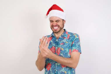 Noel Baba şapkalı genç adam ellerinde ve parmaklarında ağrı, eklem iltihabı var.