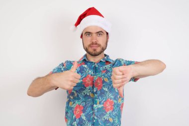 Noel Baba şapkalı genç adam baş parmağını kaldırıyor, zor bir seçim konsepti. 