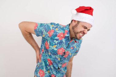 Noel Baba şapkalı genç adam sırt ağrısı çekiyor, elleriyle dokunuyor, kas ağrısı çekiyor.