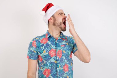 Noel Baba şapkalı genç adam bütün gününü işte geçirdikten sonra yorgun ve esniyor..