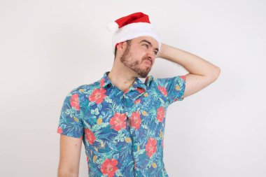 Noel Baba şapkalı genç adam soru sorup şaşırıyor. Şüpheyle kararsız, kafa kafaya düşünerek. Düşünceli kavram.