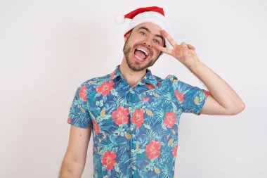 Noel Baba şapkalı genç adam barış sembolü yapıyor. Yüzünde parmaklar, gülümseyerek zaferi gösteriyor.