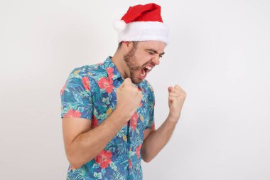 Noel Baba şapkalı genç adam kolları havada, gülümseyen ve başarı için bağıran kazanan jest yapıyor. Kutlama konsepti.