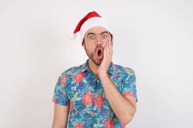 Noel Baba şapkalı genç adam çok şaşırmış görünüyor. Beklenmedik haberler karşısında şaşkına dönüyor. Yüz ifadeleri kavramı.