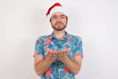 Noel Baba şapkalı genç adam avuç içi açık bir şey tutuyor ve kameraya sunuyor..