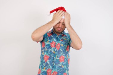 Noel Baba şapkalı genç adam aşırı çalışma yüzünden çaresiz ve stresli bir baş ağrısı çekiyor. Depresyon ve acı kavramı.