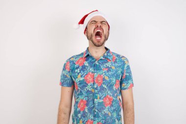 Noel Baba şapkalı genç adam kızgın ve kızgın bağırıyor sinirli ve öfkeli, öfkeyle bağırıyor. Öfke ve agresif kavram.