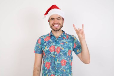 Noel Baba şapkalı genç adam kaya hareketi yapıyor ve kameraya gülümsüyor. En sevdiği konsere gitmeye hazır..