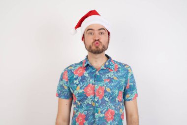 Noel Baba şapkalı genç adam dudaklarını büzüyor. İnsan yüz ifadeleri