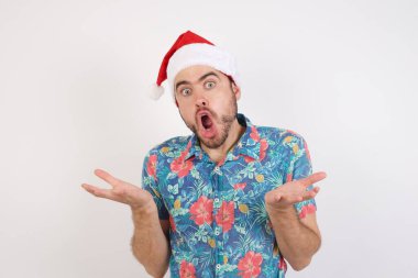 Noel Baba şapkalı genç adam şaşkınlıkla omuz silkiyor, ağzı açık, ne yapacağını bilmiyor..