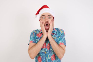 Noel Baba şapkalı korkmuş genç adamın stüdyo fotoğrafı. İnsanlar ve insan duyguları kavramı