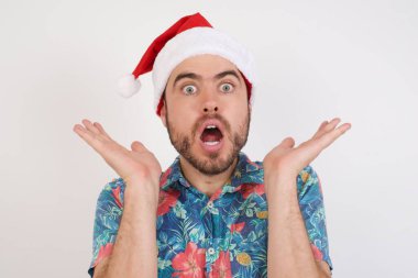 Noel Baba şapkalı genç adam belirsizlikle el kol hareketi yapar, kameraya bakar, bilmediğinden kafası karışır, insanlar, vücut dili, duygu konsepti.