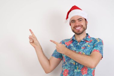 Noel Baba şapkalı genç adam işaret parmağıyla boş uzayı gösteriyor. 