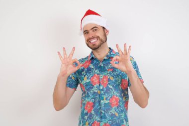 Noel Baba şapkalı genç adam iyi bir jest yapıyor ve gülümsüyor. Sakin ol, her şey mükemmel..