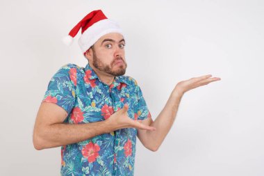 Noel Baba şapkalı genç adam tuhaf bir şey gösteriyor. Reklam kavramı.