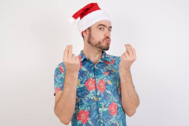 Noel Baba şapkalı genç adam elleriyle para hareketi yapıyor, maaş istiyor, milyonerlik işi yapıyor.