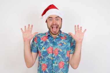 Noel Baba şapkalı genç adam sevinçten avuçlarını kaldırıyor, birinden müthiş bir hediye almaktan mutlu, yüksek sesle bağırıyor, heyecanlı beyaz erkek çığlıkları atıyor..