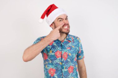 Noel Baba şapkalı genç adam alnındaki sivilceden mutsuz, siyah başlıklı çirkin enfeksiyon. Sivilce ve deri problemi