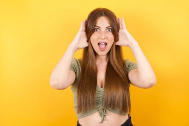 Yüzünde korku ifadesi olan, ellerini başının üstünde tutan, çenesi düşmüş, harika bir ifadesi olan genç kadın. Omg kavramı