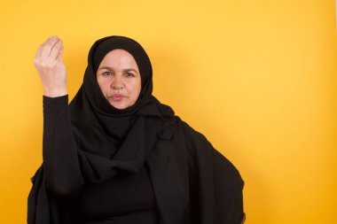 Olgun bir kadın, elinde tipik bir İtalyan jesti, kameraya bakıyor.