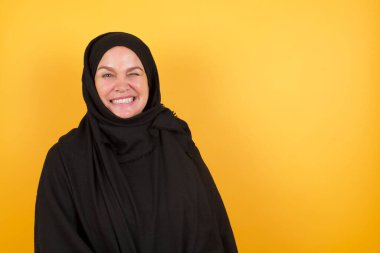 Olgun bir kadın mutlu bir şekilde gülümsüyor, kameraya şakacı bir şekilde göz kırpıyor, seninle flört ediyor. İnsan yüz ifadeleri ve duyguları