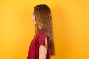 Güzel genç bir kadın yan tarafa bakıyor, rahat bir poz veriyor.  