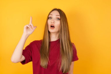 Güzel genç bir kadın başarılı bir fikirle işaret ediyor. Heyecanlı ve mutlu. Bir numara..