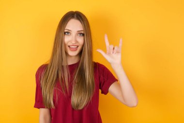 Güzel, genç bir kadın kaya hareketi yapıyor ve kameraya gülümsüyor. En sevdiği konsere gitmeye hazır..