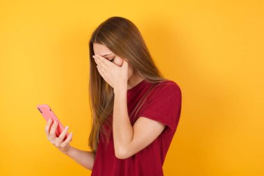 Stüdyoda elinde cep telefonu tutan üzgün bir kadın var. 