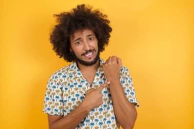 Yakışıklı genç adam kol saatini işaret ediyor, sabırsız, rahat bir ifadeyle kameraya bakıyor.