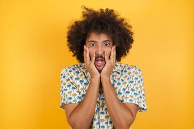 Yakışıklı genç adam heyecan ve heyecan ifade eder, çenesini indirir, elleri yanaklarında, gözleri fırlar