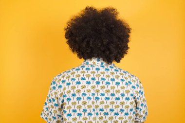 Sarı duvarın önünde duran genç yakışıklı bir adamın arka görüntüsü. Stüdyo Çekimi.