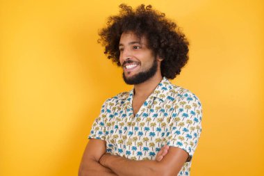 Yakışıklı genç adam kollarını kavuşturuyor, yana bakıyor. 