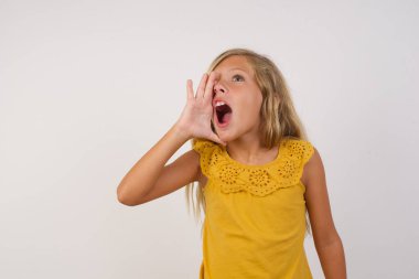 cute little girl shouting and screaming loud to side with hand on mouth. Communication concept. clipart