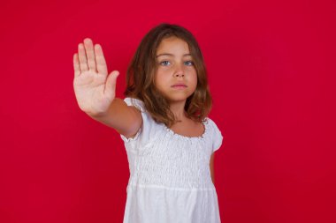 Sevimli küçük kız avuç içiyle jesti durduruyor. Yüzünde olumsuz ve ciddi bir jest olan uyarı ifadesi 